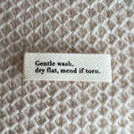 Štítek "Gentle wash, dry flat, mend if torn."